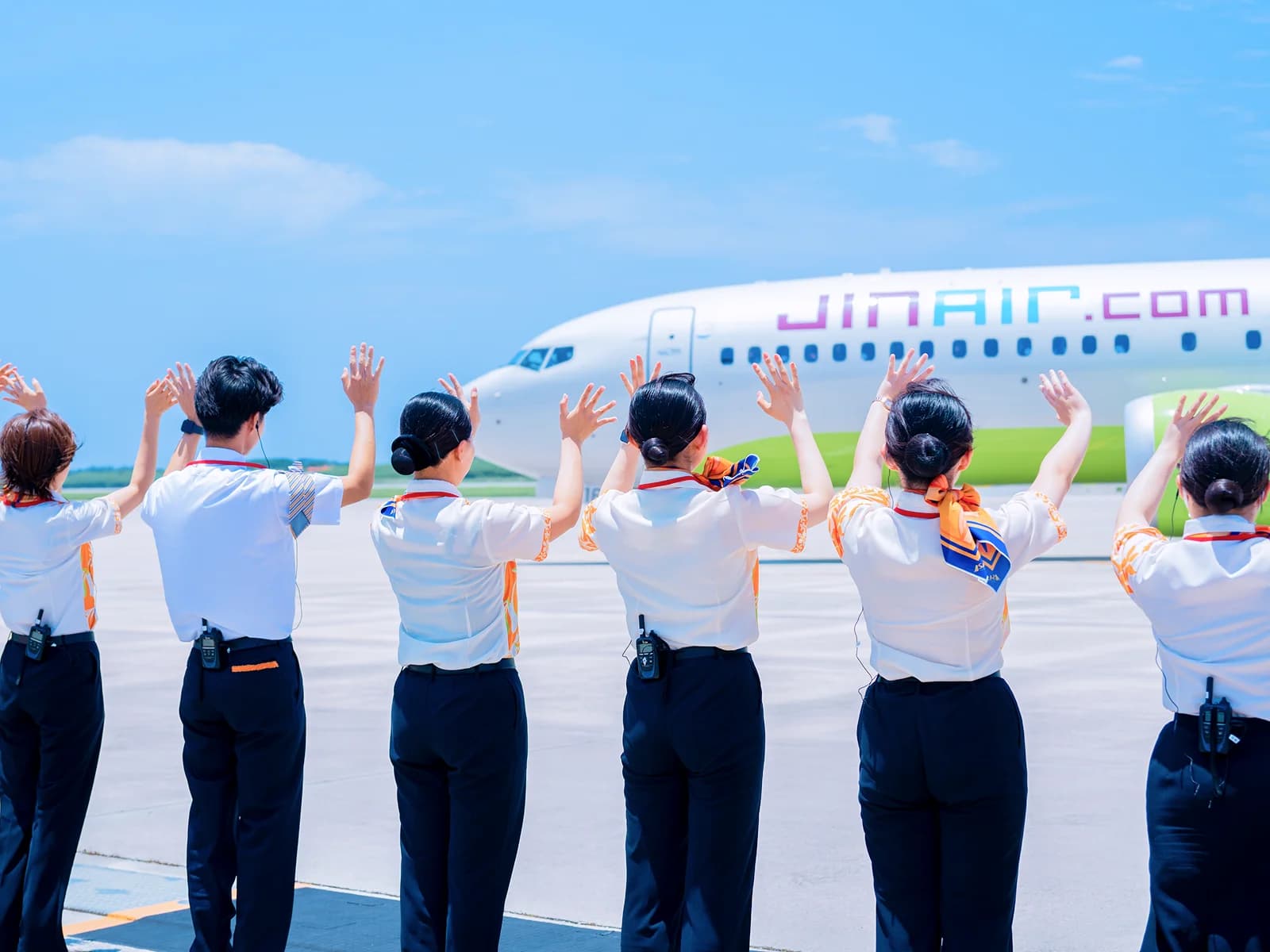 駐機場で航空機に手を振って見送るスタッフたち