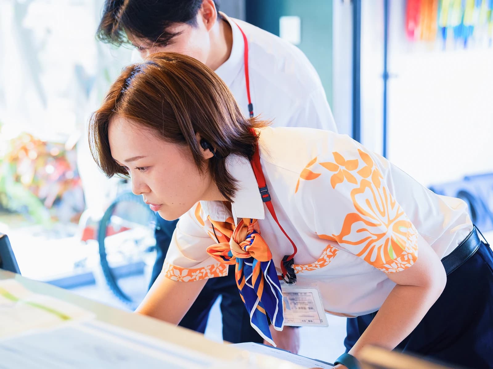 先輩と並んで手元を確認する旅客ハンドリングのスタッフ
