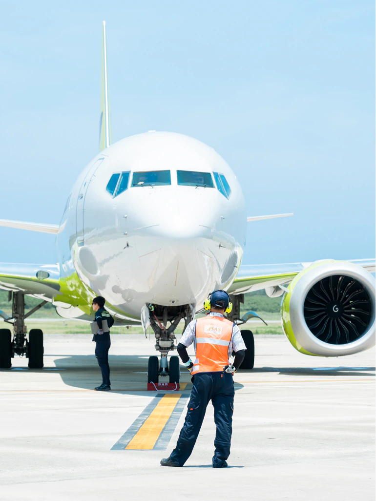 航空機の前で誘導にあたるランプハンドリングスタッフ